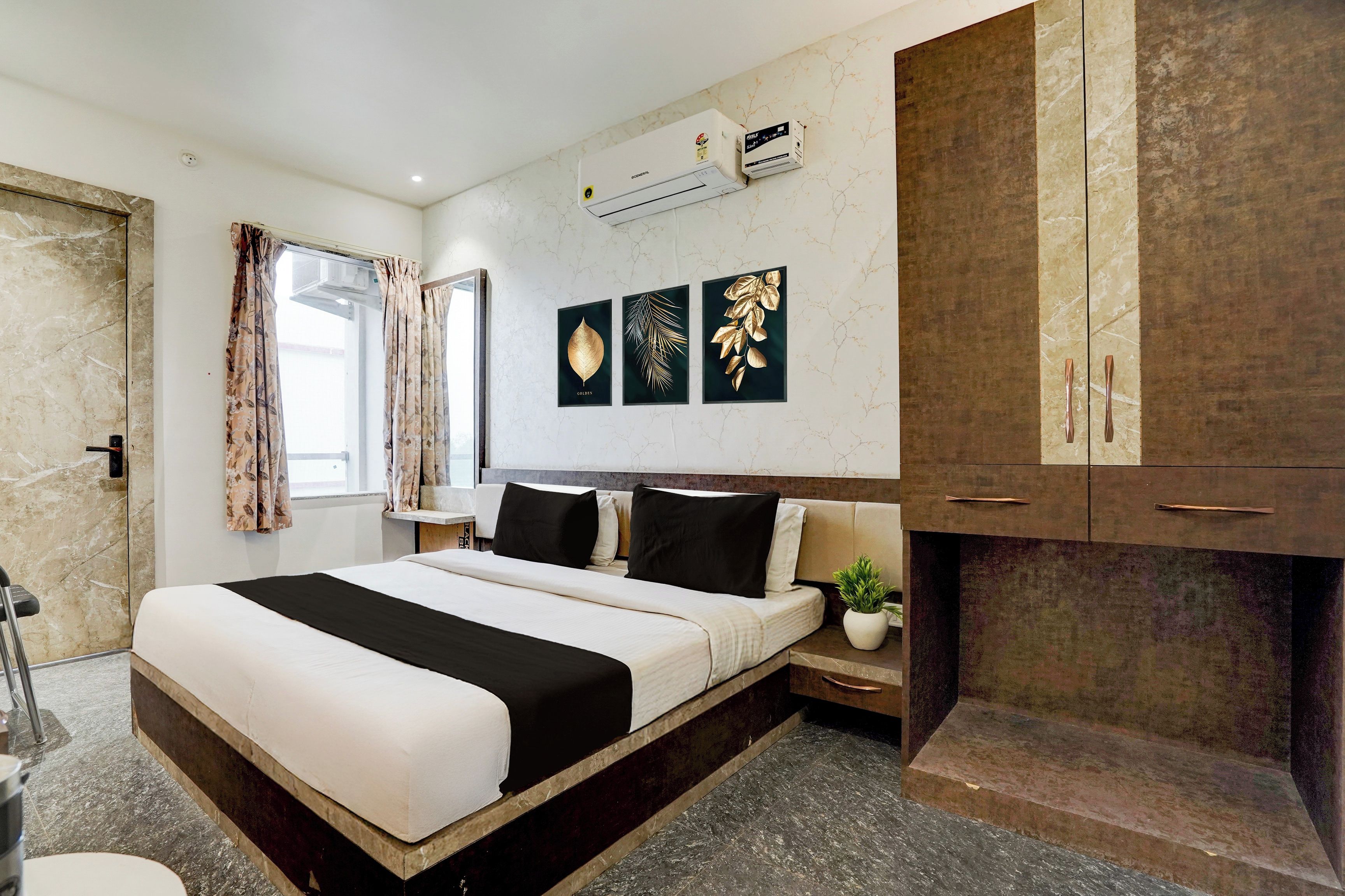 Una habitación de hotel con cama, mesita de noche, planta en maceta y armario.