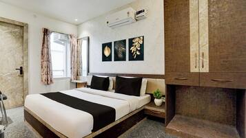 Una habitación de hotel con cama, mesita de noche, planta en maceta y armario.
