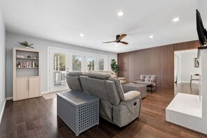 A modern living room with a sectional sofa, a ceiling fan, and a wooden floor. - Hillside Family Retreat • 3BR/2BA • Near the Zoo (Oakland)