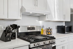 A modern kitchen with white cabinets, a stainless steel stove, and a black microwave. - Hillside Family Retreat · 3BR + Library · Near the Oakland Zoo (Oakland)