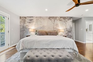 A bedroom with a large bed, two bedside lamps, a tufted bench, and a wall mural. - Hillside Family Retreat • 3BR/2BA • Near the Zoo (Oakland)