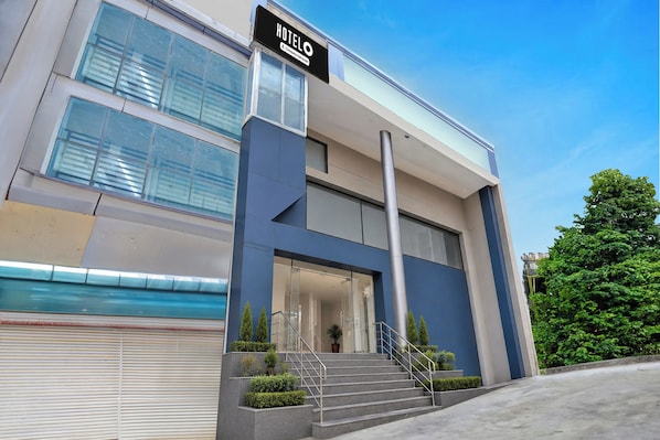A modern hotel with a prominent 'HOTEL' sign, a glass entrance, and a staircase leading to the entrance. - Hotel O Sector 110 Noida (Noida)