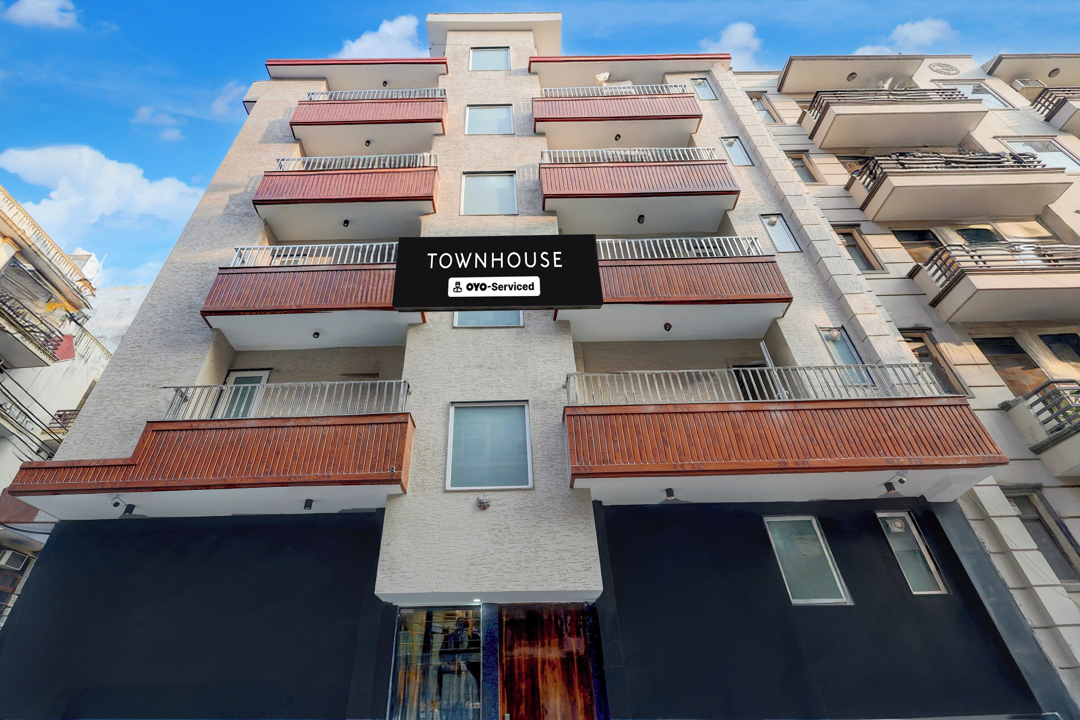 Un immeuble résidentiel à plusieurs étages, doté de balcons, avec une enseigne indiquant « IMMEUBLE D’HABITATION » et les services « OYO-Serviced ».