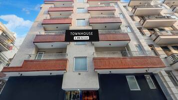 A multi-story residential building with balconies, a sign indicating 'TOWNHOUSE' and 'OYO-Serviced' services.