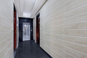 A hallway with a black floor, white walls, and a door at the end. - Townhouse Phase 3 DLF Cyber City (Gurugram)