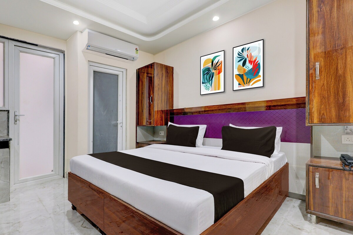 Una habitación de hotel con una cama, un armario, un escritorio con teléfono y dos obras de arte en la pared.