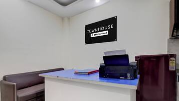 A reception desk with a sign indicating 'Townhouse OYO-Serviced' in a room with a couch and a refrigerator.