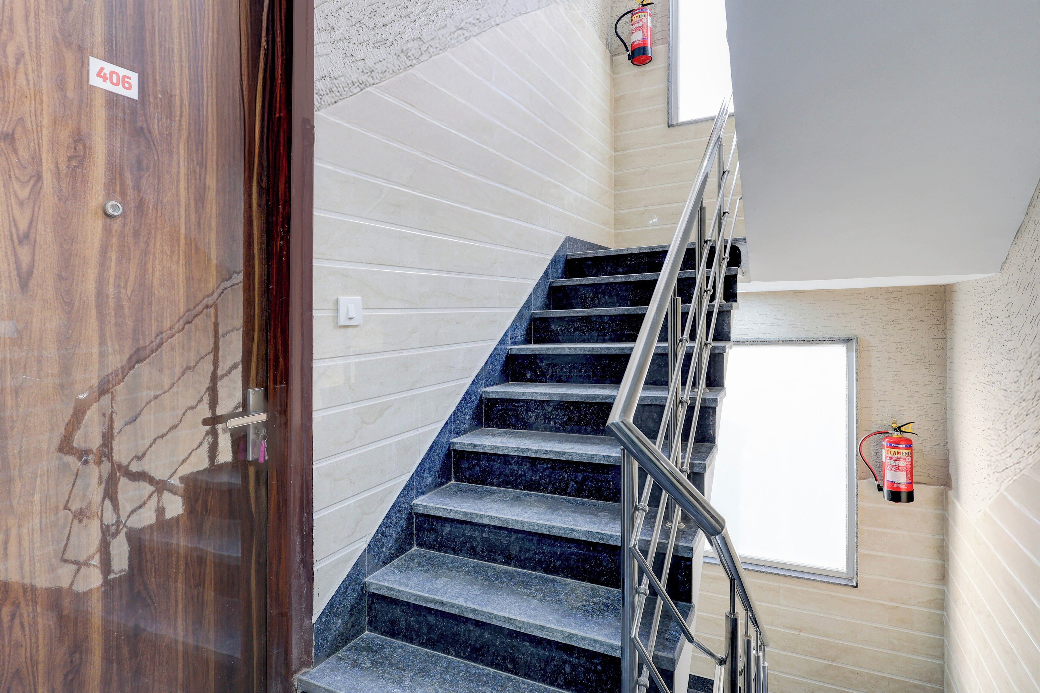 A staircase with a metal railing, a fire extinguisher mounted on the wall, and a door with a number sign.