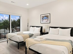 A hotel room with two beds, a city view, a framed picture on the wall, and a balcony.