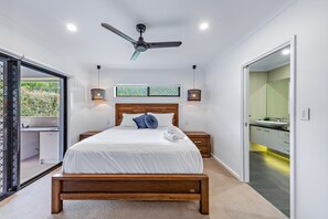 Ein modernes Schlafzimmer mit einem hölzernen Bett, einem Deckenventilator und Blick ins Freie.
