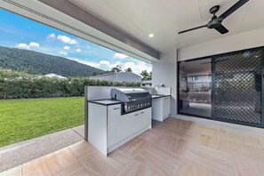 Eine moderne Küche mit integriertem Grill, großen Fenstern und Blick auf eine grüne Landschaft.