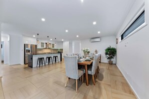 Et moderne køkken med en central ø, barstole og et spiseområde med et træbord og stole.