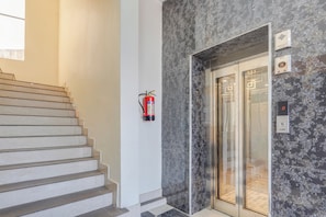 A staircase leading to an elevator with a fire extinguisher mounted on the wall.