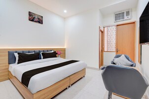 Una habitación de hotel con una cama, una silla, una puerta y un aire acondicionado instalado en la pared.