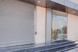A modern building entrance with a closed roller shutter door and a glass door leading to an interior.