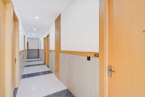 A corridor with wooden doors, numbered room signs, and a tiled floor.