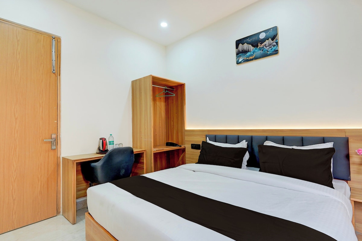A bedroom with a bed, a desk, a chair, a wardrobe, and a painting on the wall.