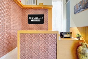A reception desk with a geometric patterned wall, a sign reading 'TOWNHOUSE Company-Serviced', and a printer on the counter.