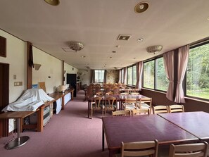 A dining area with tables and chairs, a counter with a cash register, and a view of the outdoors through large windows. - Spacious Chalet in Yuzawa Ski Storage, Free Parking for Group Trips (Yuzawa)