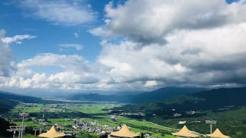 A panoramic view of a mountainous landscape with a village below, featuring several large tents and a clear sky.