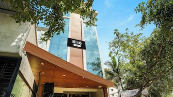 L’entrée d’un hôtel, avec une façade moderne en verre, une enseigne et un auvent en bois.