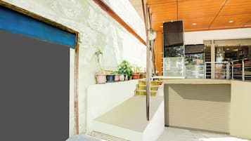 Un intérieur moderne avec un escalier menant à un deuxième étage, une porte d’entrée en verre et des plantes en pot sur le palier.
