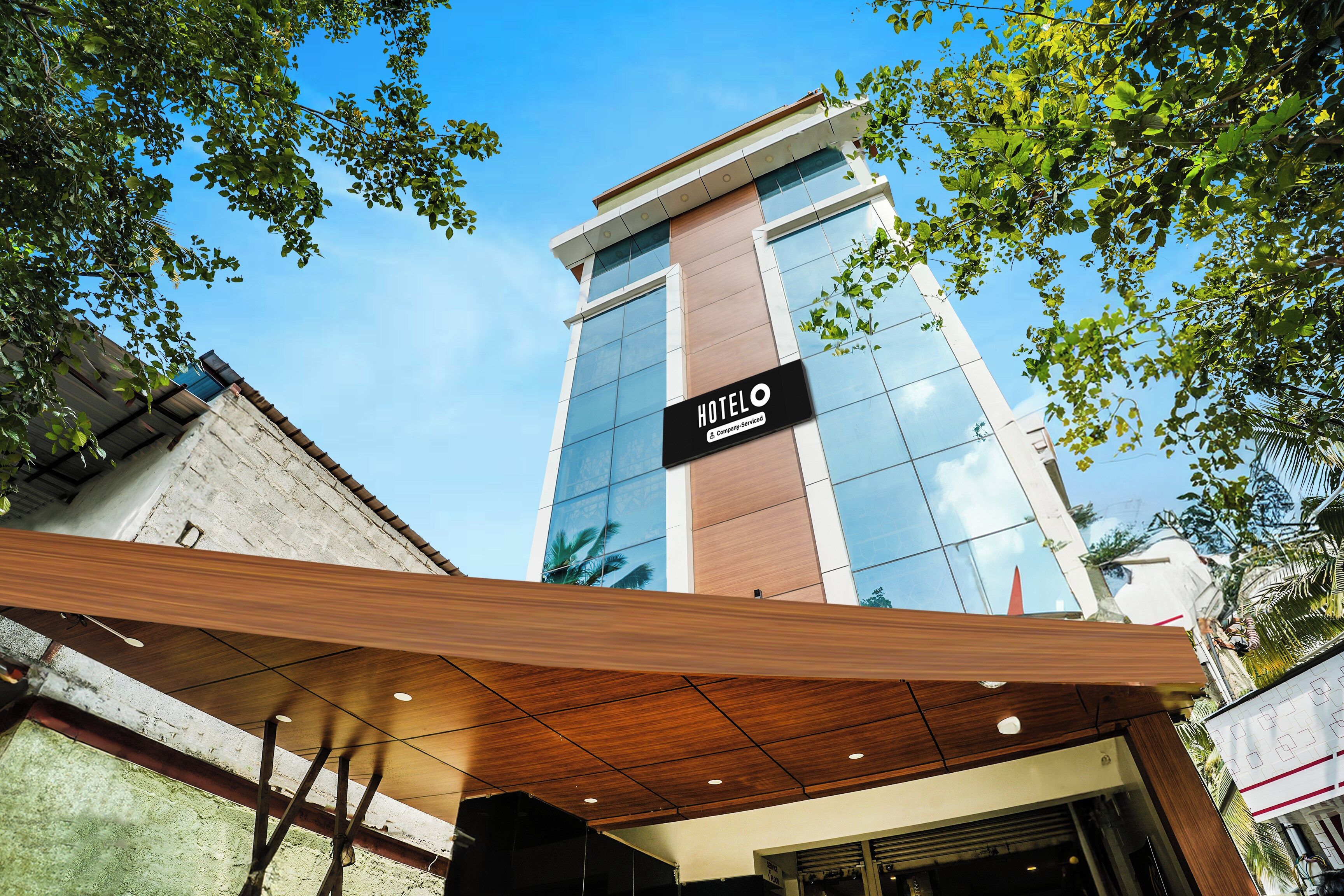 A modern hotel building with a prominent 'HOTEL O' sign, large windows, and a covered entrance area.