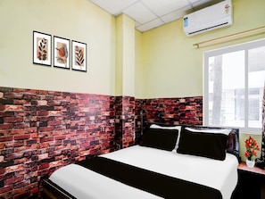 A hotel room with a brick-patterned headboard, a bed with black and white bedding, a window with a view, and three framed pictures on the wall. - Deluxe Ganeshguri Nayanpur Rainbow (Guwahati)
