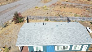 Un immeuble résidentiel doté d’un toit en métal, d’une cour clôturée et offrant une vue dégagée sur le paysage environnant.