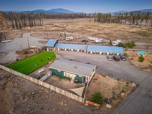 A lodge with a green building, a fenced yard, and a parking area with RVs. - The Lassen Home, 3 bedrooms near Lake Almanor (Chester)