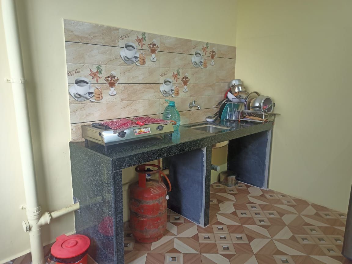 Una cocina con estufa a gas, pileta y salpicadero de azulejos.