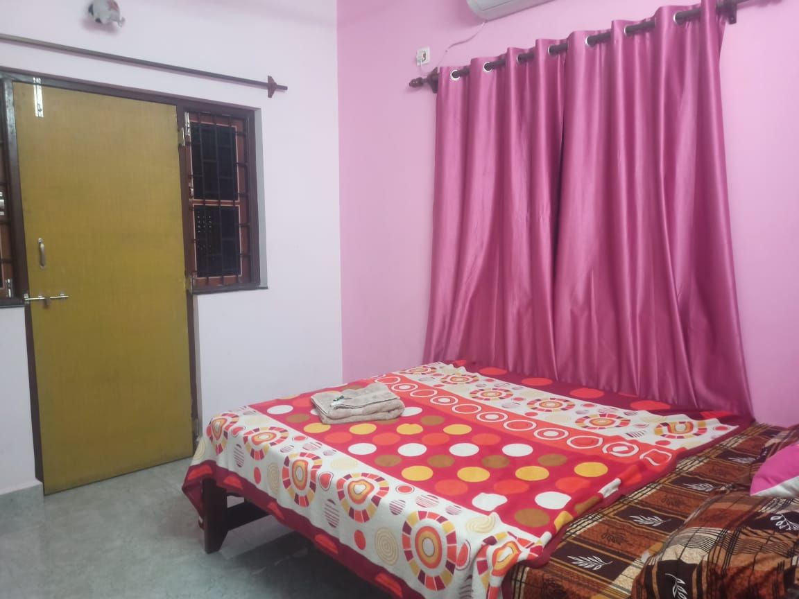Un dormitorio con cama, una ventana con reja, una puerta y una cortina.