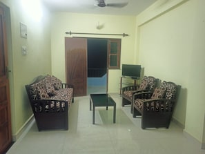 A living room with a sofa set, a coffee table, and a television.