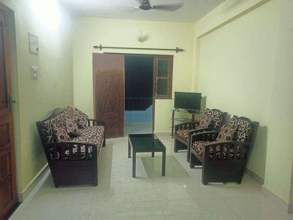 A living room with a sofa set, a coffee table, and a television.