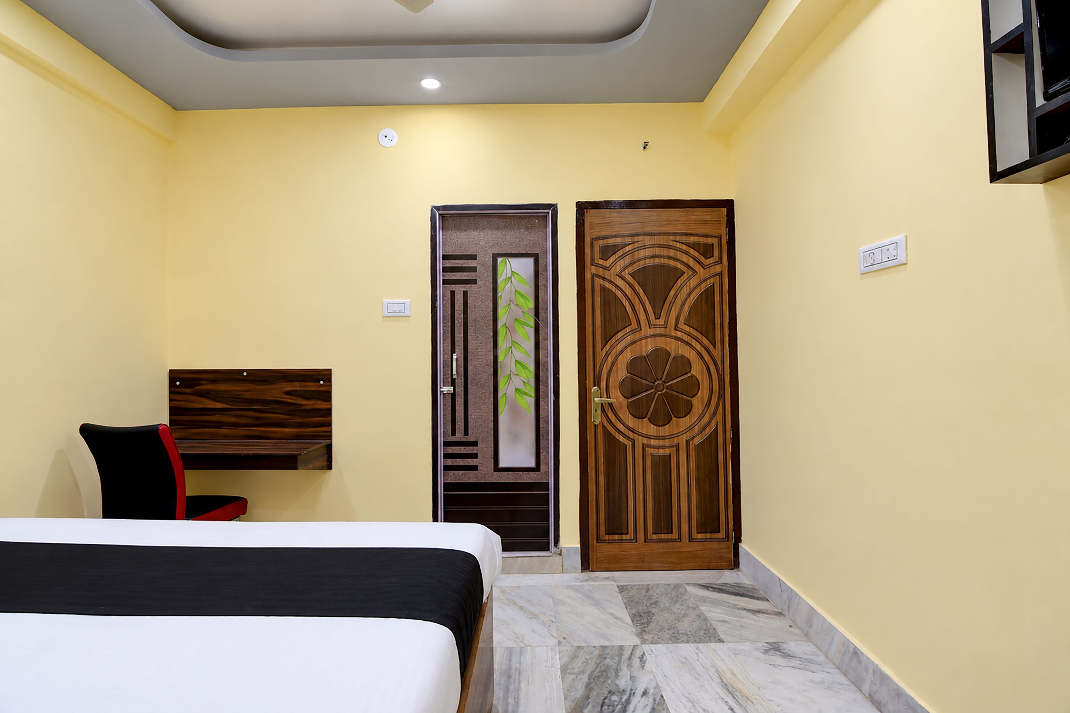 A hotel room with a bed, a desk, and a door with a decorative panel.