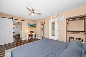 A bedroom with a bed, a desk, a chair, a ceiling fan, and a painting on the wall. - Jayhawk House - 5 min to KU/DWTN (Lawrence)
