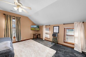 A room with a ceiling fan, a bed, a desk, a chair, a framed picture, and a window with blinds. - Jayhawk House - 5 min to KU/DWTN (Lawrence)
