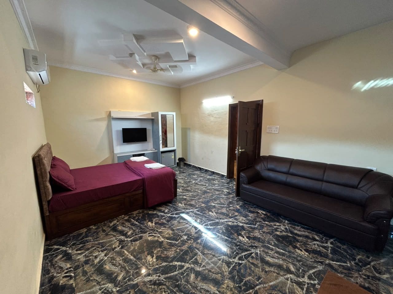 A room with a bed, a sofa, a TV, and a ceiling fan.