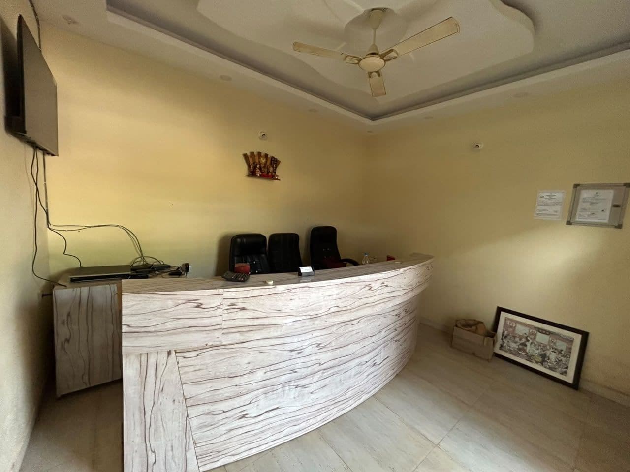 A reception desk with a curved design, a ceiling fan, and a framed picture on the wall.