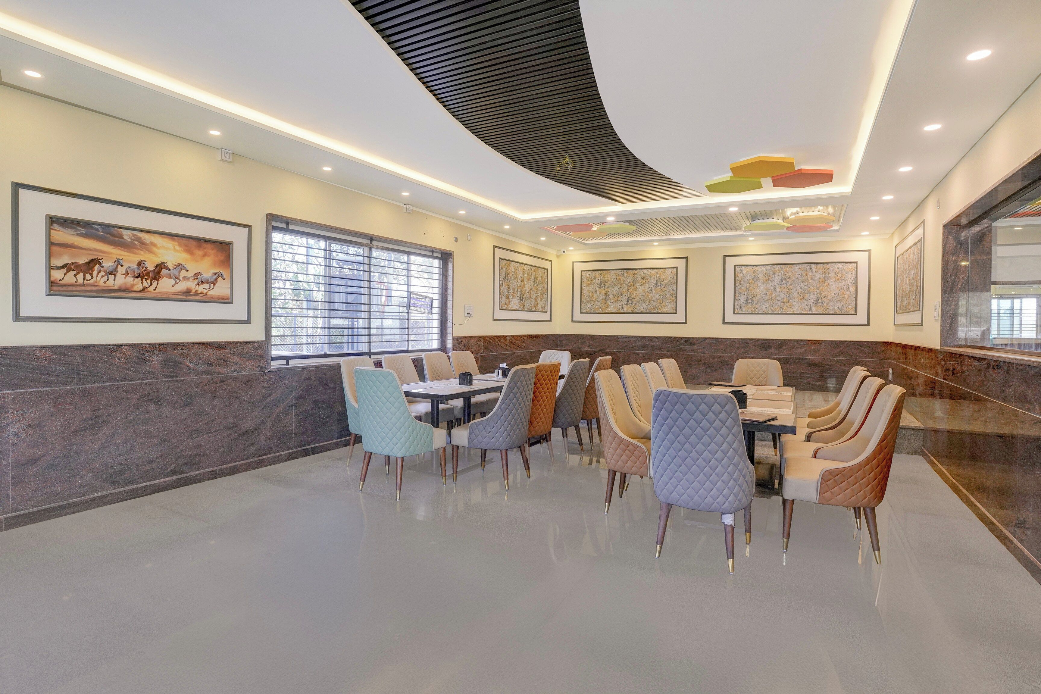 A conference room with a marble wall, a large window with blinds, and a ceiling with recessed lighting and a geometric design.