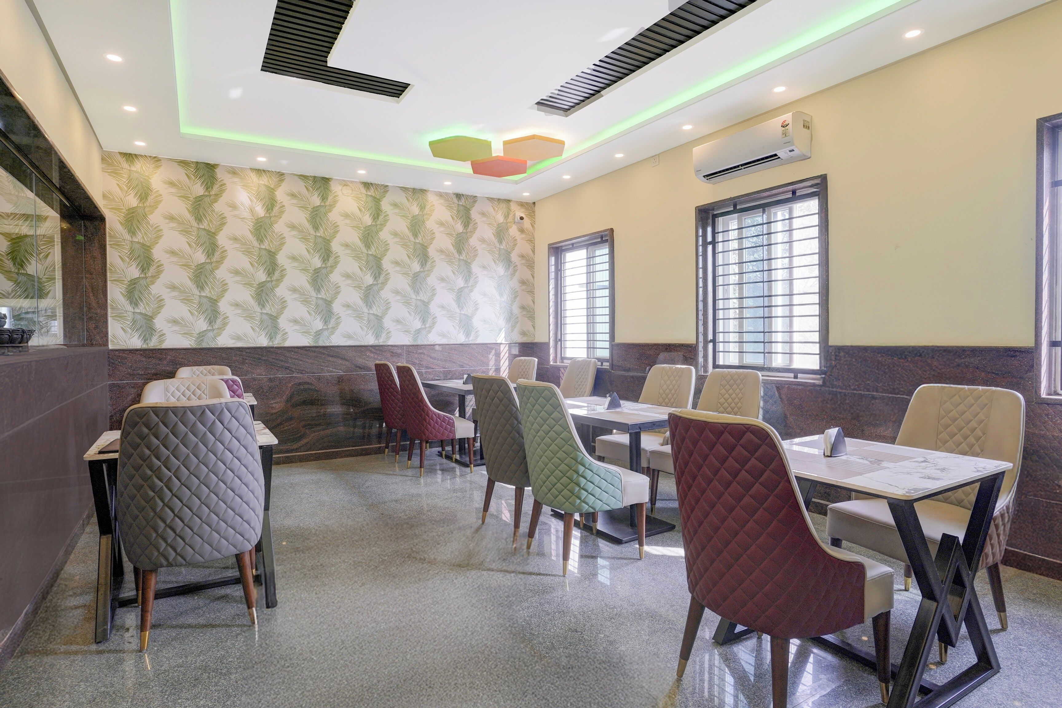 L’intérieur d’un restaurant au design moderne, avec un mur orné de motifs, un plafond doté d’un éclairage encastré et une variété de types de sièges.