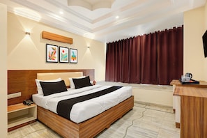 A hotel room with a wooden bed, a nightstand, a desk with a kettle, and a window with curtains. - Hotel O Karni Mata Mandir Udaipur (Udaipur)