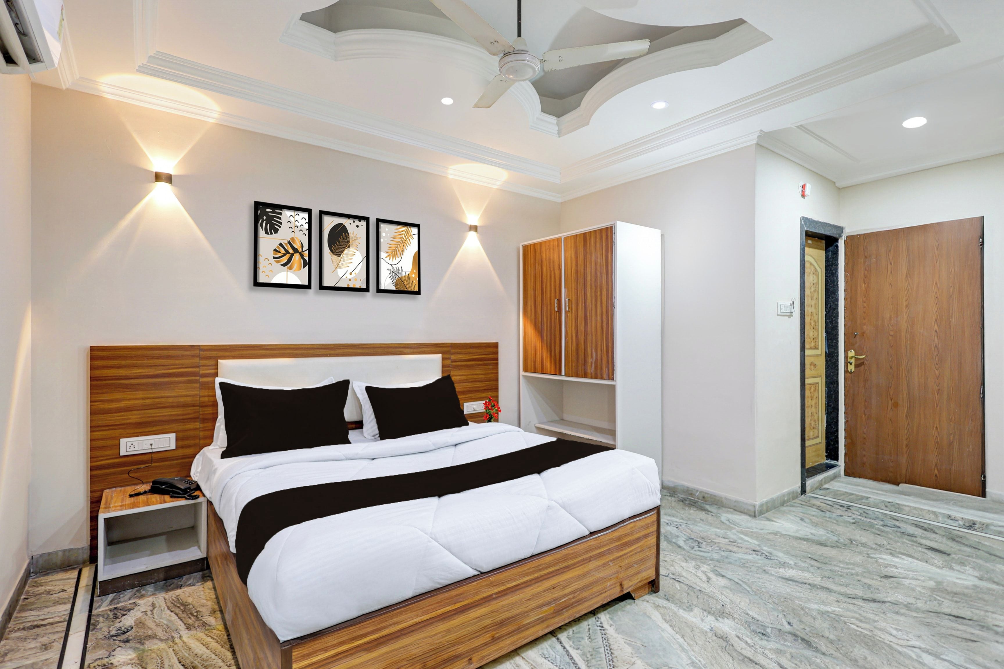 Una habitación de hotel con cama, mesitas de noche, armario y ventilador de techo.