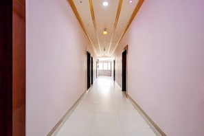 A long, narrow hallway with a tiled floor and a ceiling with recessed lighting.