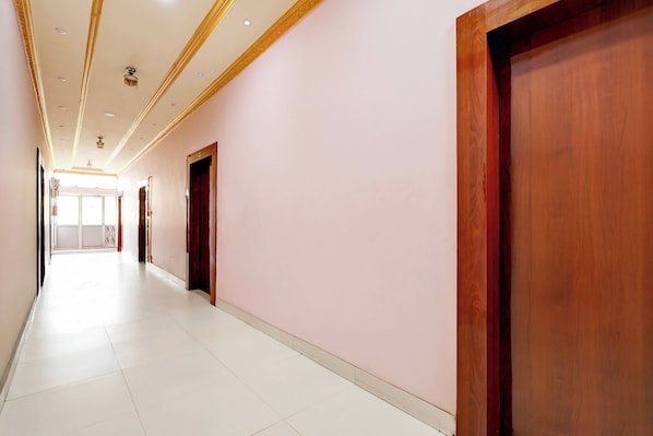 A long, narrow hallway with white tiled flooring and wooden doors.