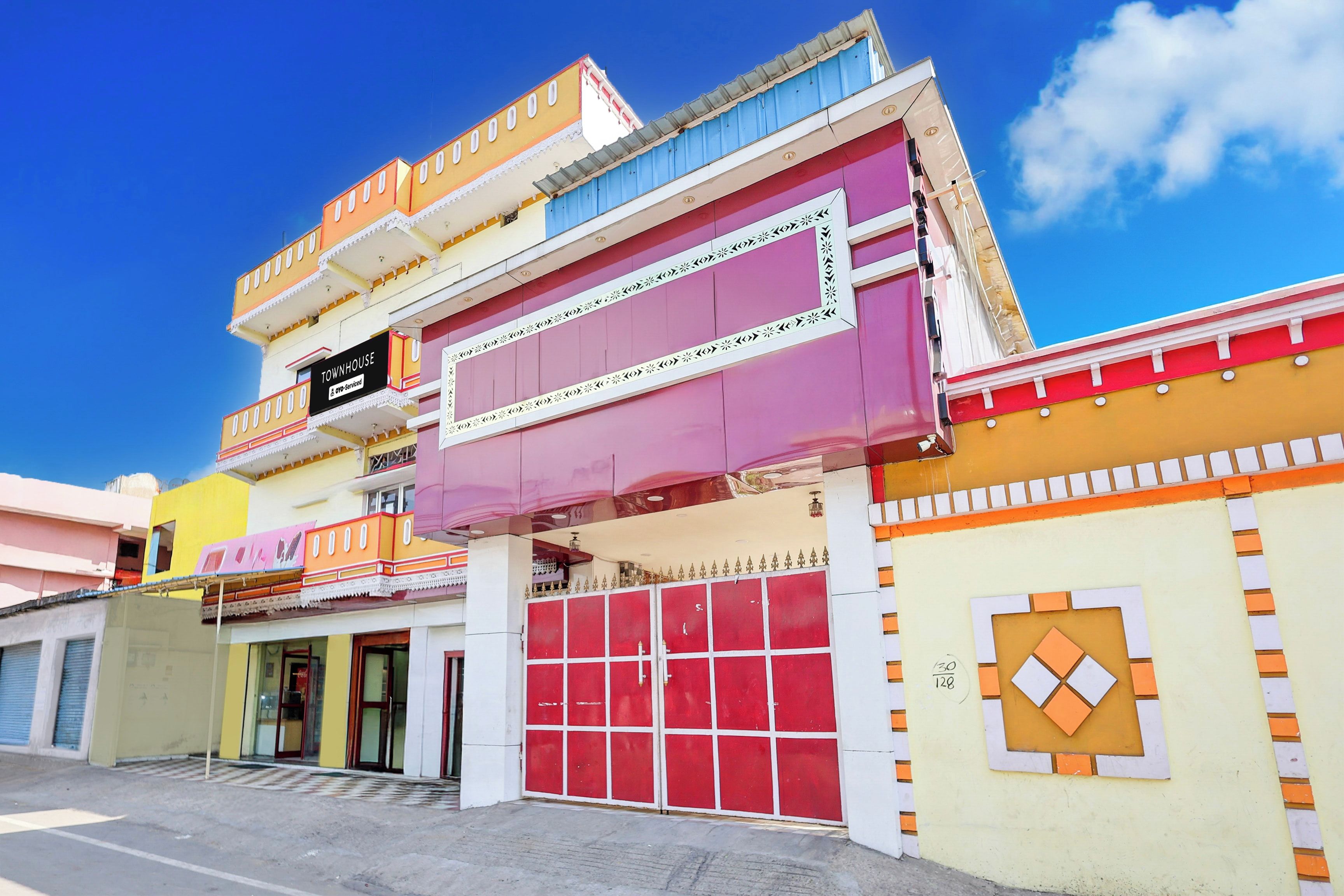 A multi-story building with a prominent red garage door, a sign indicating a townhouse, and a clear blue sky in the background.