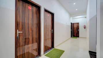 Un couloir avec deux portes en bois, chacune portant un numéro, qui donnent accès à des pièces.