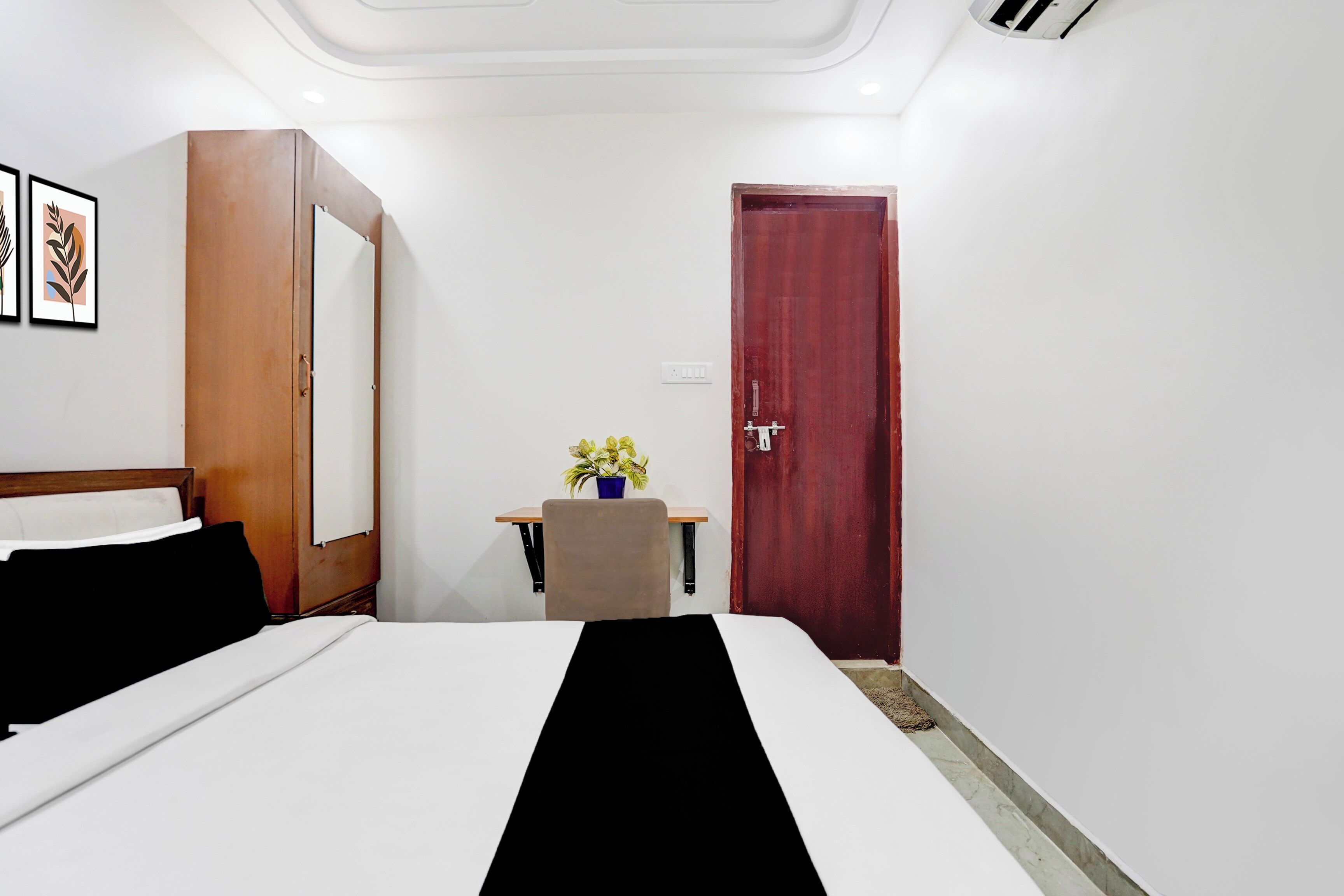 Ein Hotelzimmer mit einem Bett, einem Schreibtisch, einem Stuhl, einer Tür und einem an der Wand befestigten Lichtschalter.