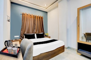 A hotel room with a bed, a bedside table with a kettle and cups, a mirror, and a tray with cups. - Collection O Iskcon Prayagraj (Prayagraj)