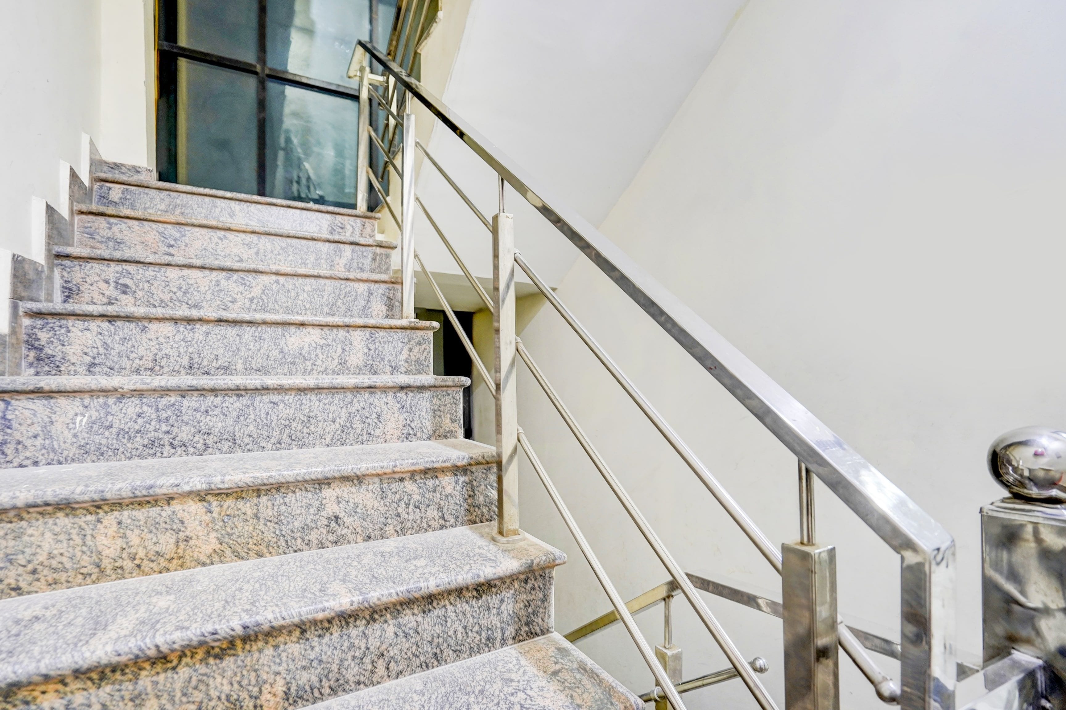 Una escalera con escalones de granito y barandilla de metal.